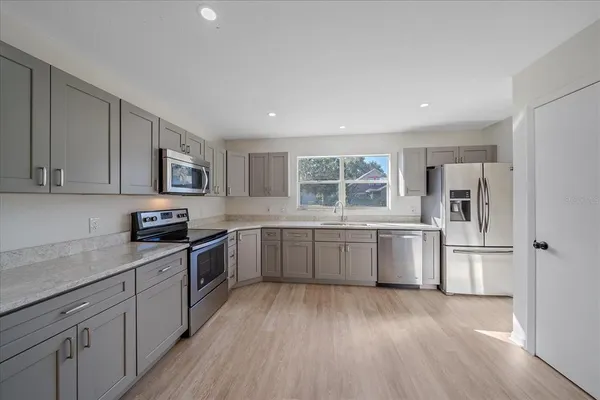 a kitchen with a sink wooden floor and stainless steel appliances