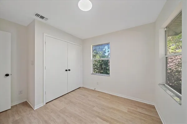 a view of an empty room with a window and wooden floor