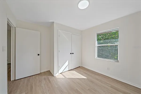 a view of an empty room with wooden floor and a window