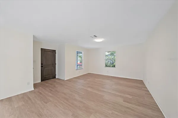 an empty room with wooden floor and windows