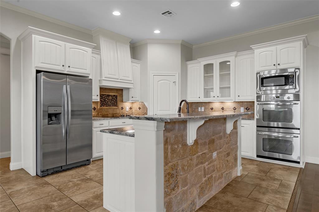 144 Ellis Farm Road Hewitt, TX 76643 - Photo 13 of 36 Kitchen featuring a stone-clad island with granite countertops, stainless steel appliances, white cabinetry, and tile flooring