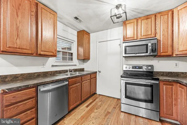 a kitchen with stainless steel appliances granite countertop wooden cabinets stove top oven and sink