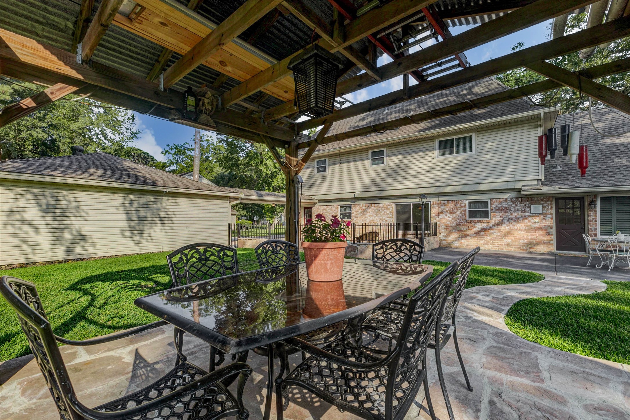 6710 Falling Waters Drive Spring, TX 77379 - Photo 44 of 46 This photo features a spacious backyard with a covered patio/gazebo, complete with a stylish outdoor dining set. The area is well-maintained, offering lush green grass and a paved walkway leading to the house, perfect for outdoor entertaining.