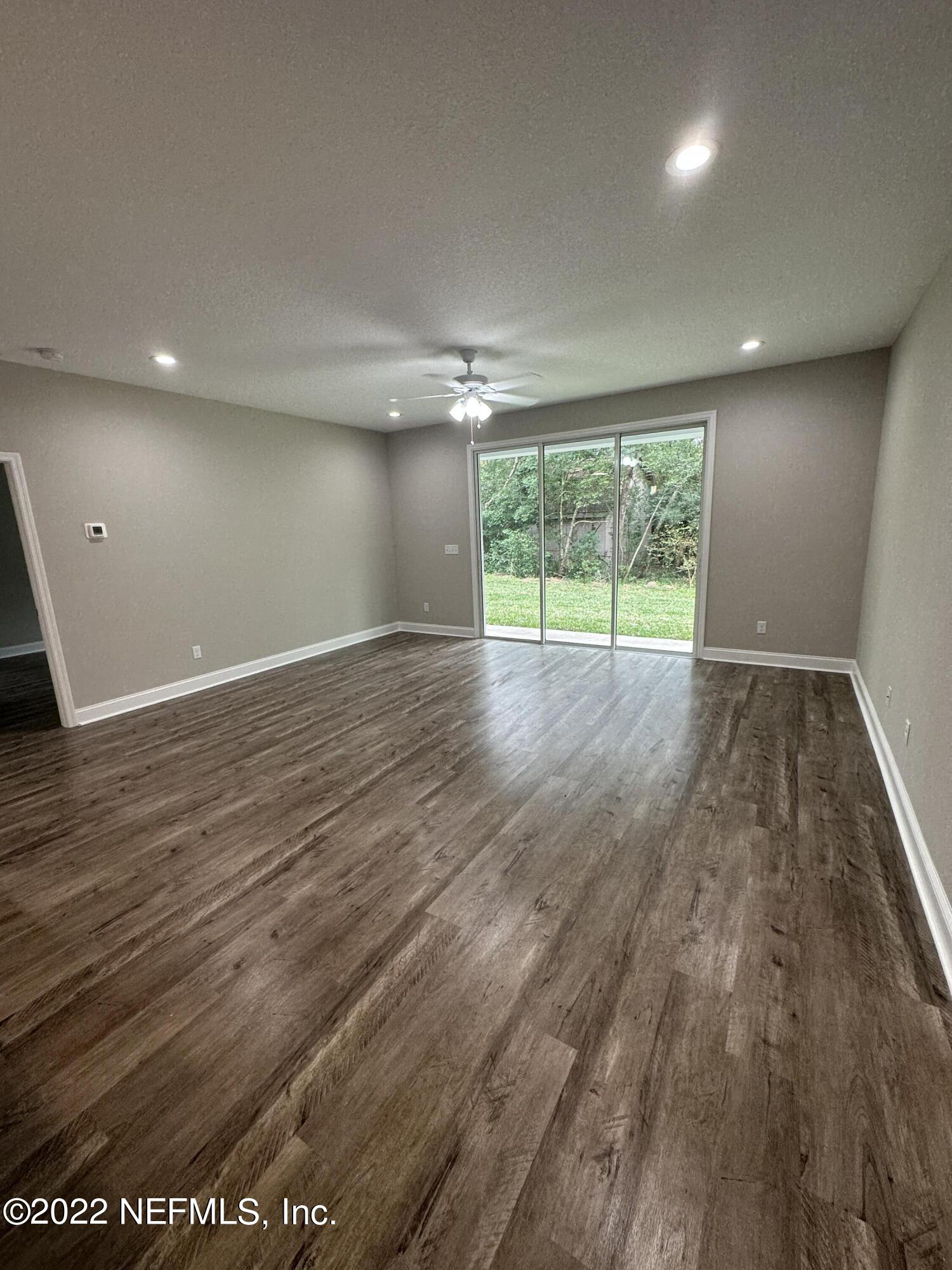 6458 Heidi Road Jacksonville, FL 32277 - Photo 13 of 26 an empty room with wooden floor and windows