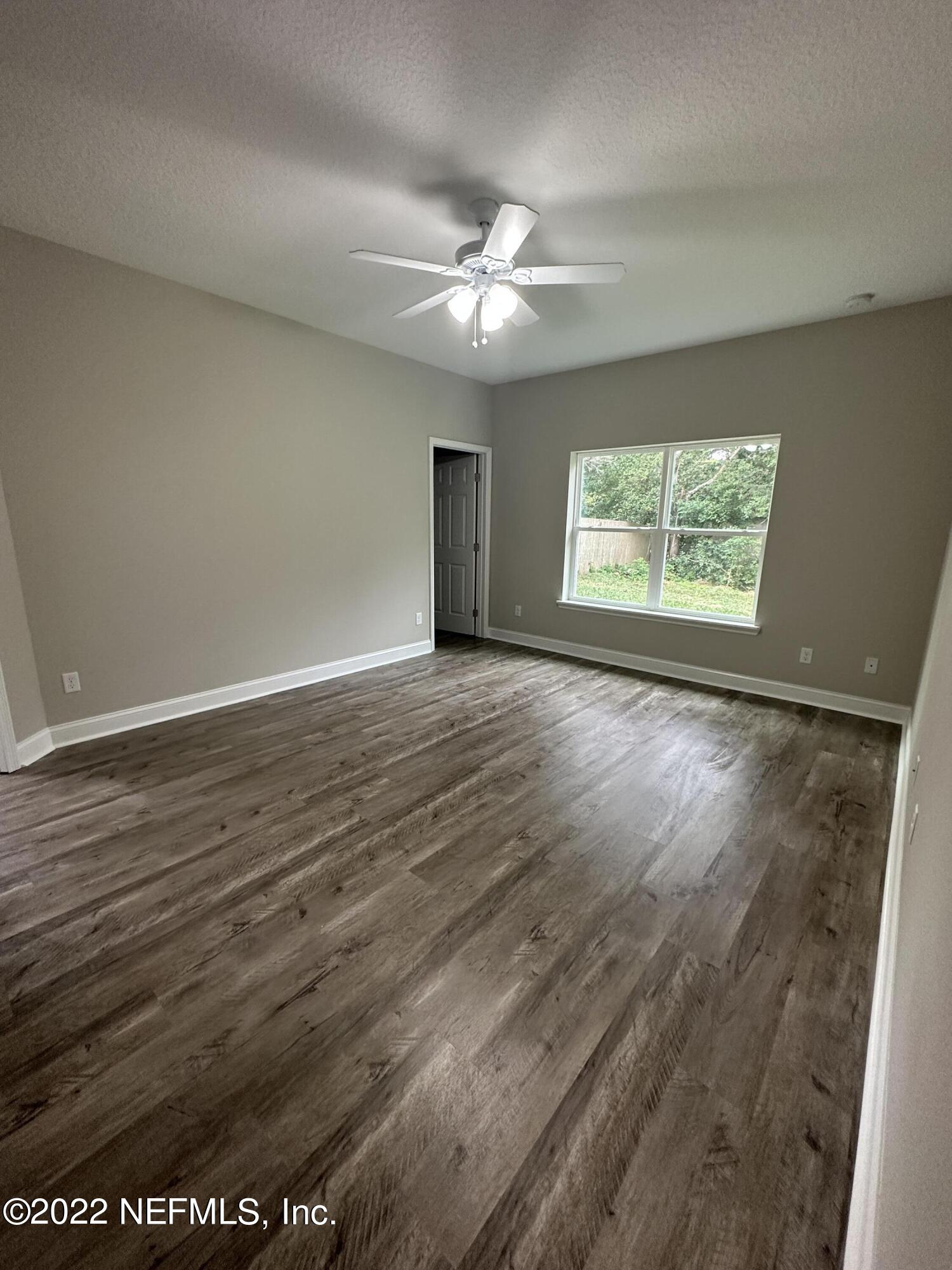 6458 Heidi Road Jacksonville, FL 32277 - Photo 14 of 26 an empty room with wooden floor chandelier fan and windows