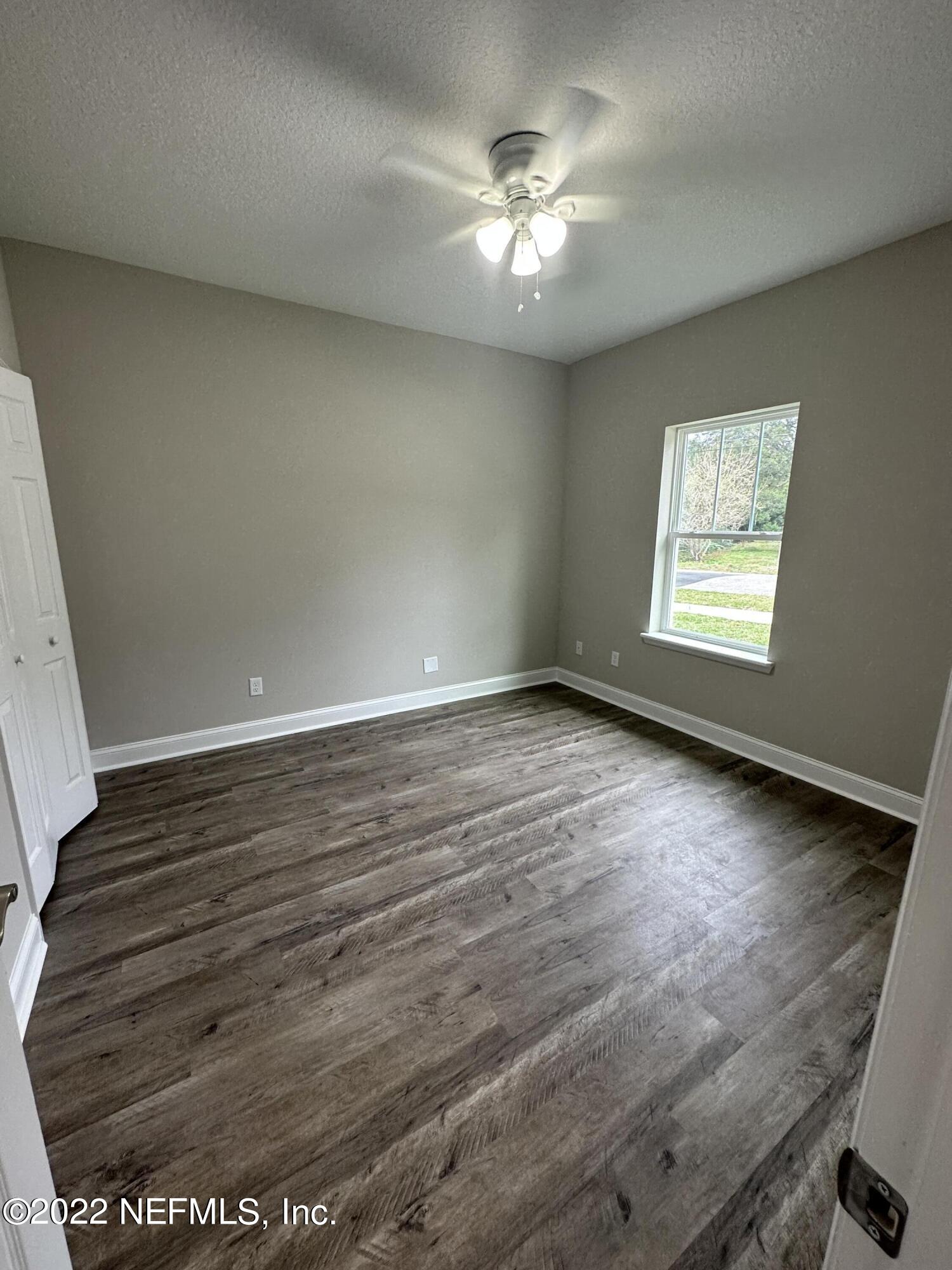 6458 Heidi Road Jacksonville, FL 32277 - Photo 21 of 26 an empty room with wooden floor and windows