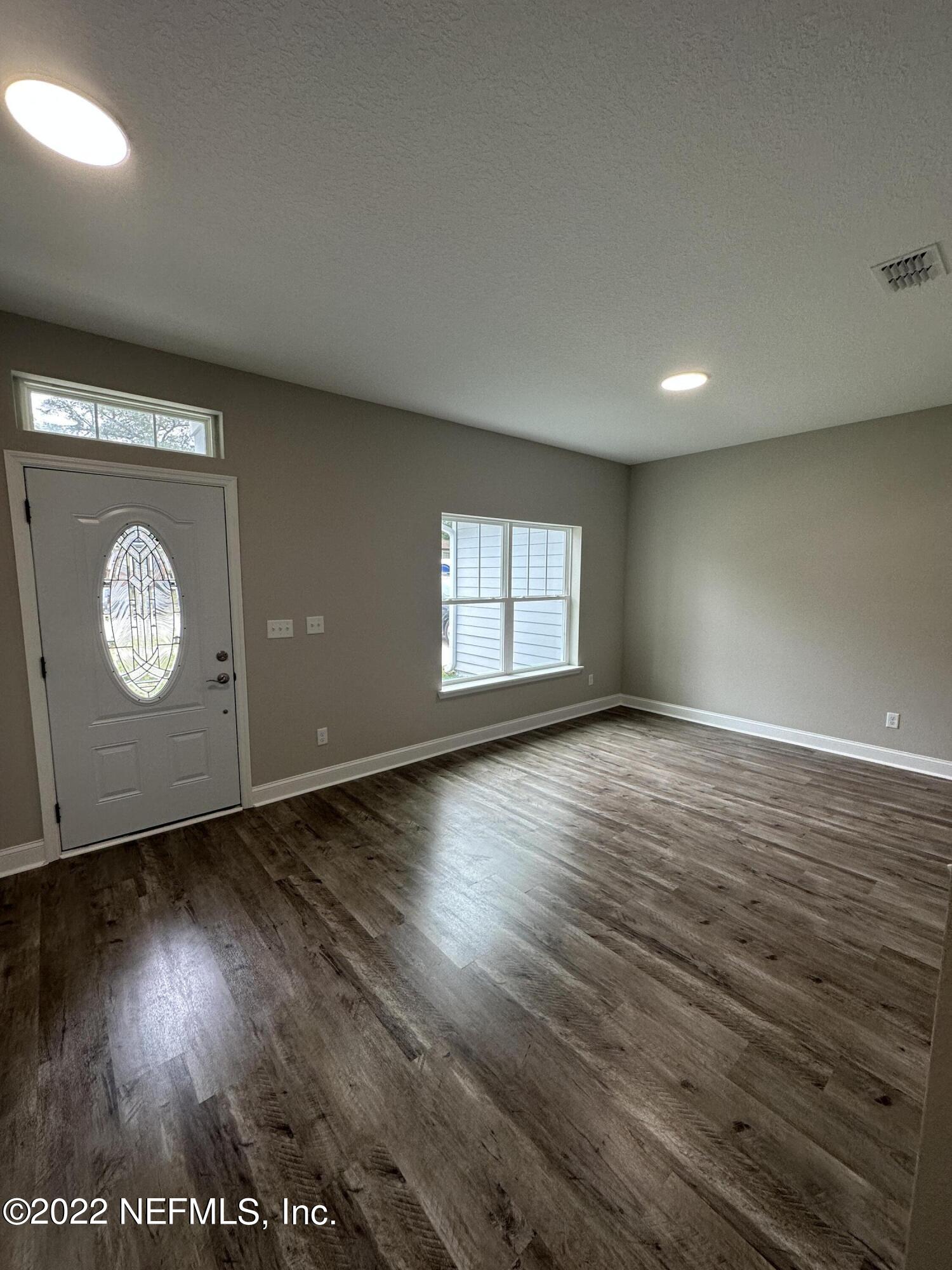 6458 Heidi Road Jacksonville, FL 32277 - Photo 3 of 26 an empty room with wooden floor and windows