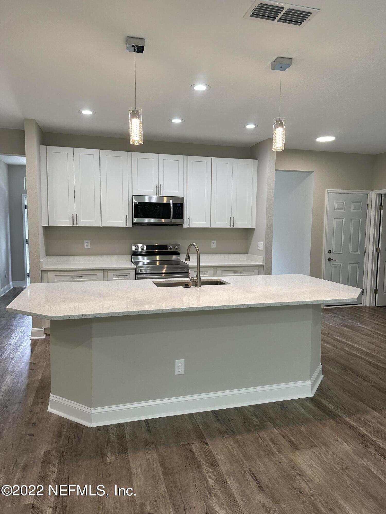 6458 Heidi Road Jacksonville, FL 32277 - Photo 4 of 26 a view of kitchen with stainless steel appliances granite countertop a stove a sink a refrigerator and white cabinets with wooden floor