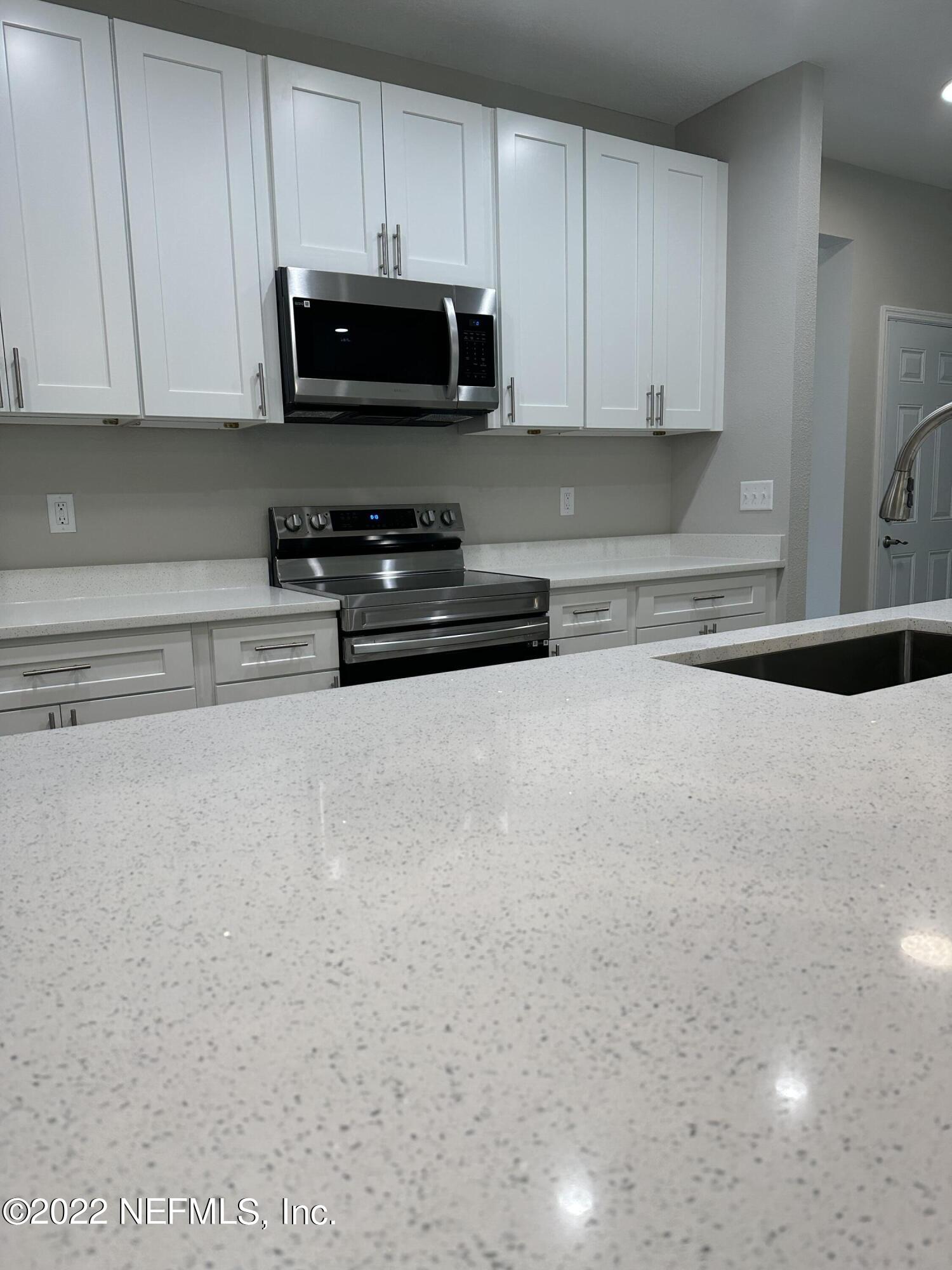 6458 Heidi Road Jacksonville, FL 32277 - Photo 10 of 26 a kitchen with stainless steel appliances granite countertop a stove a microwave a sink and cabinets