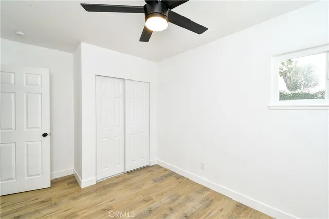 an empty room with a ceiling fan and wooden floor