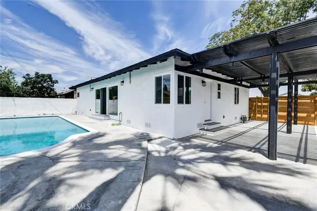 a house with a white house next to a large tree with wooden fence