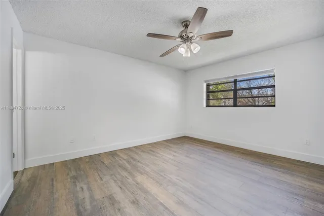 an empty room with wooden floor fan and windows