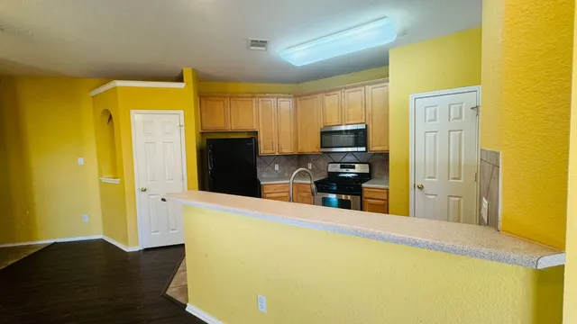 a view of a kitchen with wooden floor and electronic appliances