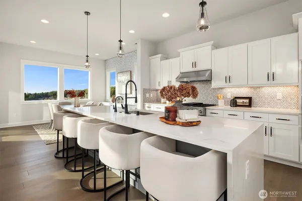 a kitchen with stainless steel appliances kitchen island a table chairs in it white cabinets and a wooden floors