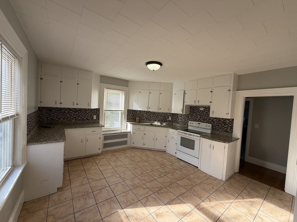 148 George Street, Unit 2 Medford, MA 02155 - Photo 3 of 26 a kitchen with granite countertop white cabinets and white appliances