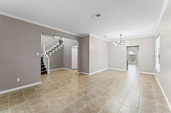 a view of an empty room with kitchen and a window