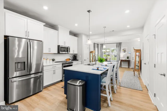 a kitchen with stainless steel appliances a refrigerator a stove a sink a dining table and chairs