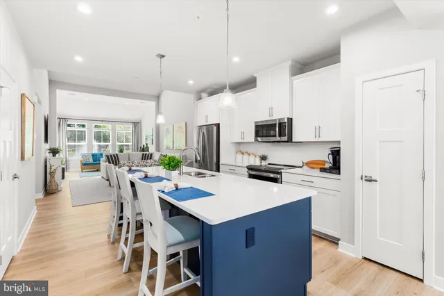 a kitchen with a sink a stove a refrigerator and white cabinets with wooden floor