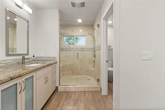 a bathroom with a granite countertop sink a toilet and shower