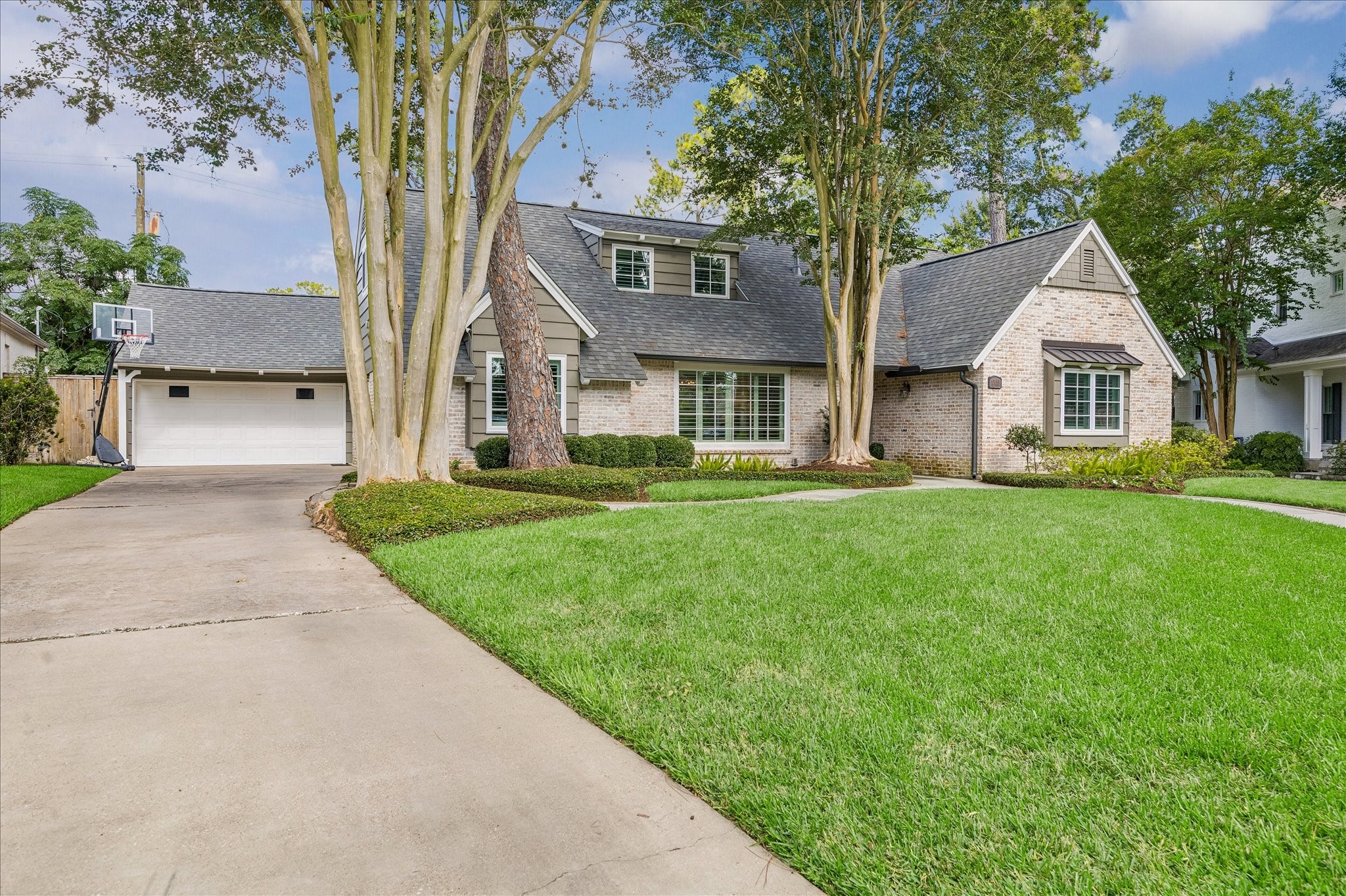 12615 Taylorcrest Road Houston, TX 77024 - Photo 3 of 29 It includes a two-car garage and a spacious driveway, set on a lush green lawn with mature trees for added privacy and curb appeal.