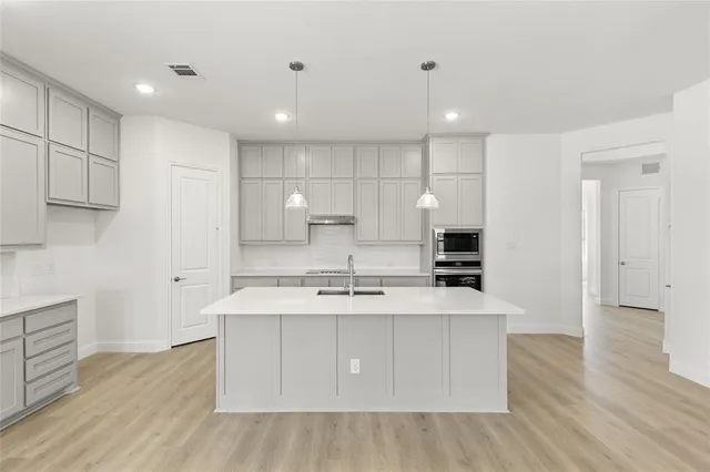 a large kitchen with stainless steel appliances kitchen island a large counter top and wooden floors