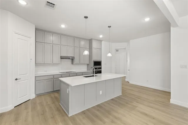 a large kitchen with kitchen island a sink a stove a refrigerator and white cabinets