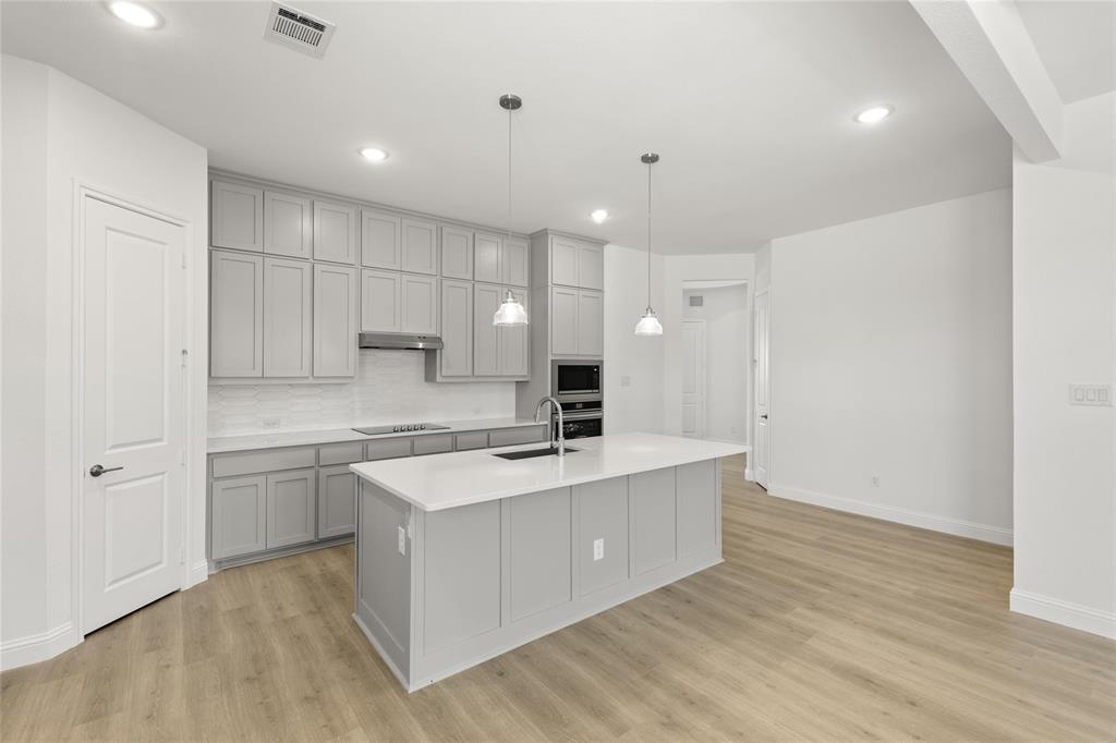 4017 Eagles Bluff Road Midlothian, TX 76065 - Photo 11 of 31 a large kitchen with kitchen island a sink a stove a refrigerator and white cabinets