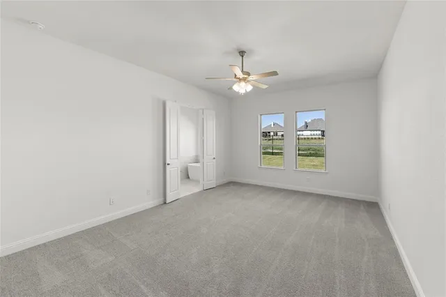 an empty room with windows and ceiling fan