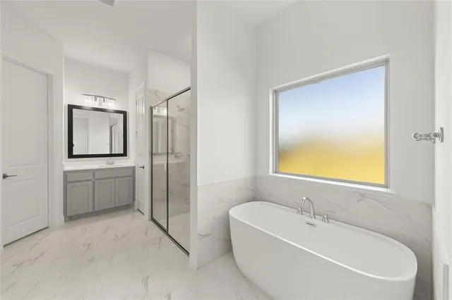 a spacious bathroom with a tub sink and mirror