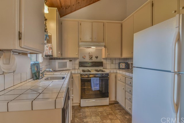 347 Donner Drive Crestline, CA 92325 - Photo 8 of 27 a kitchen with stainless steel appliances granite countertop a refrigerator sink stove and white cabinets