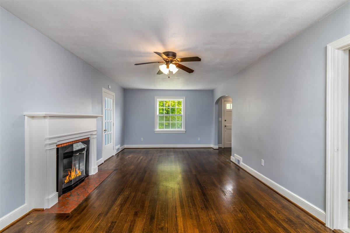 3223 Lawndale Road Roanoke, VA 24018 - Photo 6 of 37 an empty room with wooden floor a chandelier fan and a fireplace