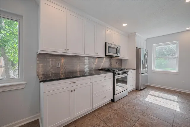 a kitchen with granite countertop white cabinets and window