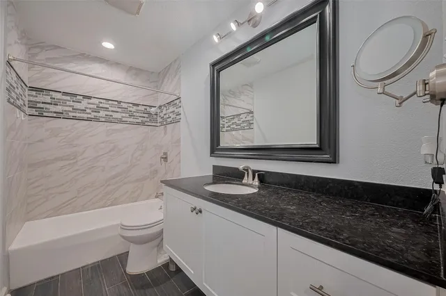 a bathroom with a granite countertop sink mirror vanity and toilet