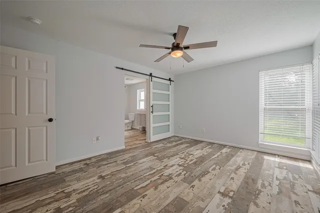 a view of empty room with wooden floor and fan