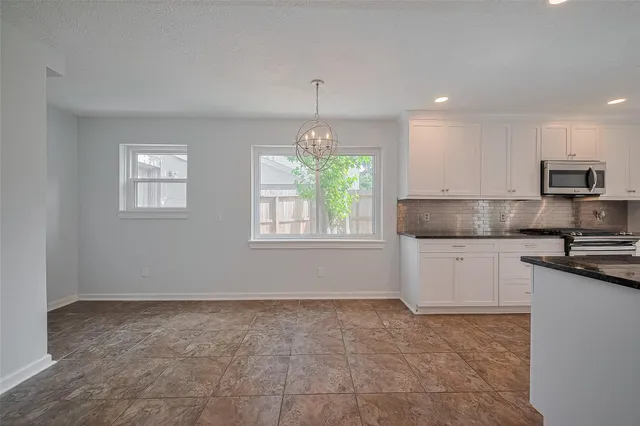 a kitchen with granite countertop a stove a sink and a refrigerator
