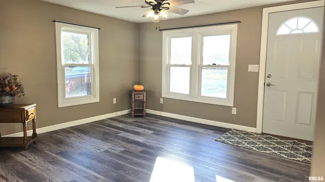 a view of an empty room with window and wooden floor