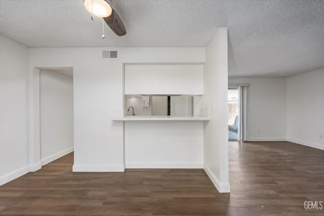 a view of an empty room with wooden floor and cabinet