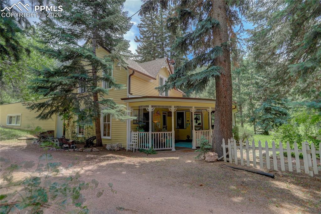 a view of a house with a large tree and wooden fence