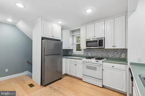 a kitchen with granite countertop white cabinets and stainless steel appliances