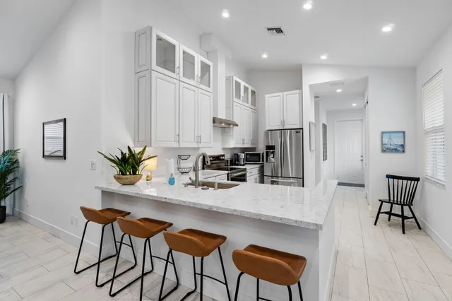 a kitchen with stainless steel appliances kitchen island granite countertop a dining table chairs and refrigerator