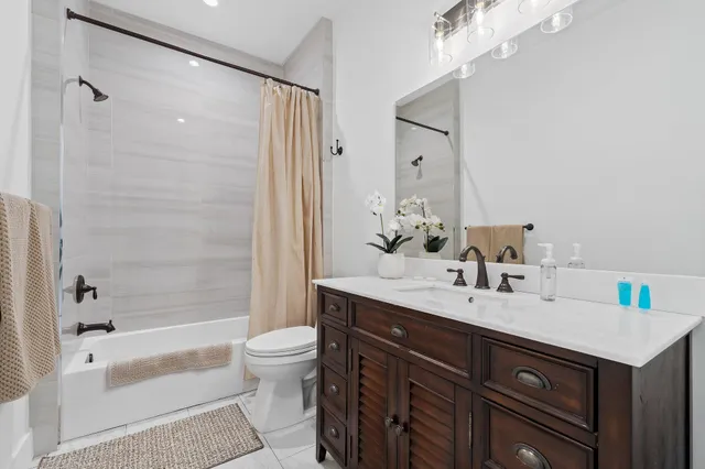 a bathroom with a bathtub shower sink vanity mirror and toilet