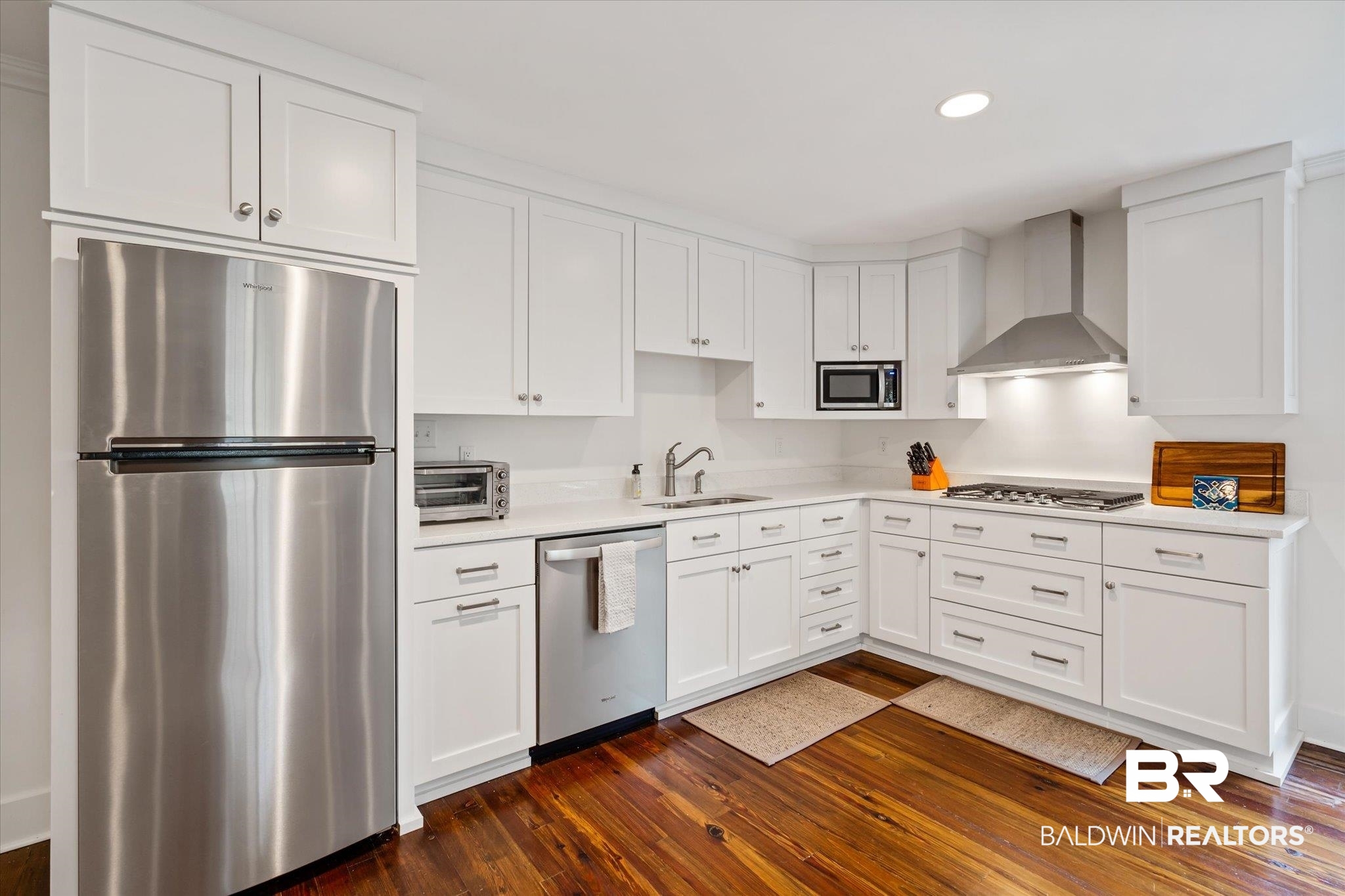 2228 Riverside Drive Mobile, AL 36605 - Photo 38 of 51 Kitchen featuring dark hardwood / wood-style floors, wall chimney exhaust hood, appliances with stainless steel finishes, sink, and white cabinetry