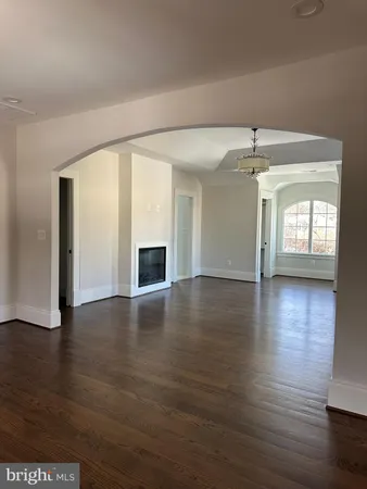 an empty room with wooden floor fireplace and windows
