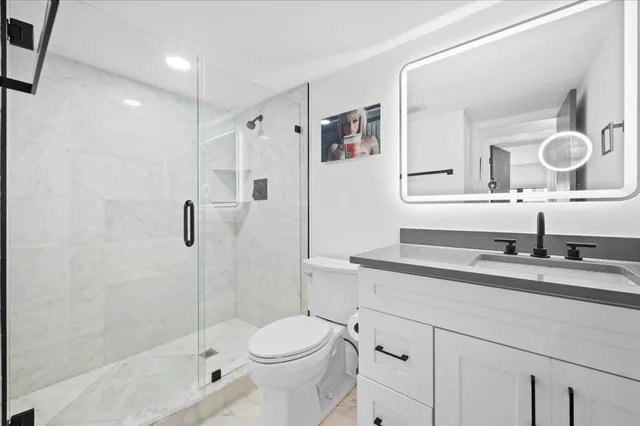 a bathroom with a granite countertop sink toilet mirror and shower