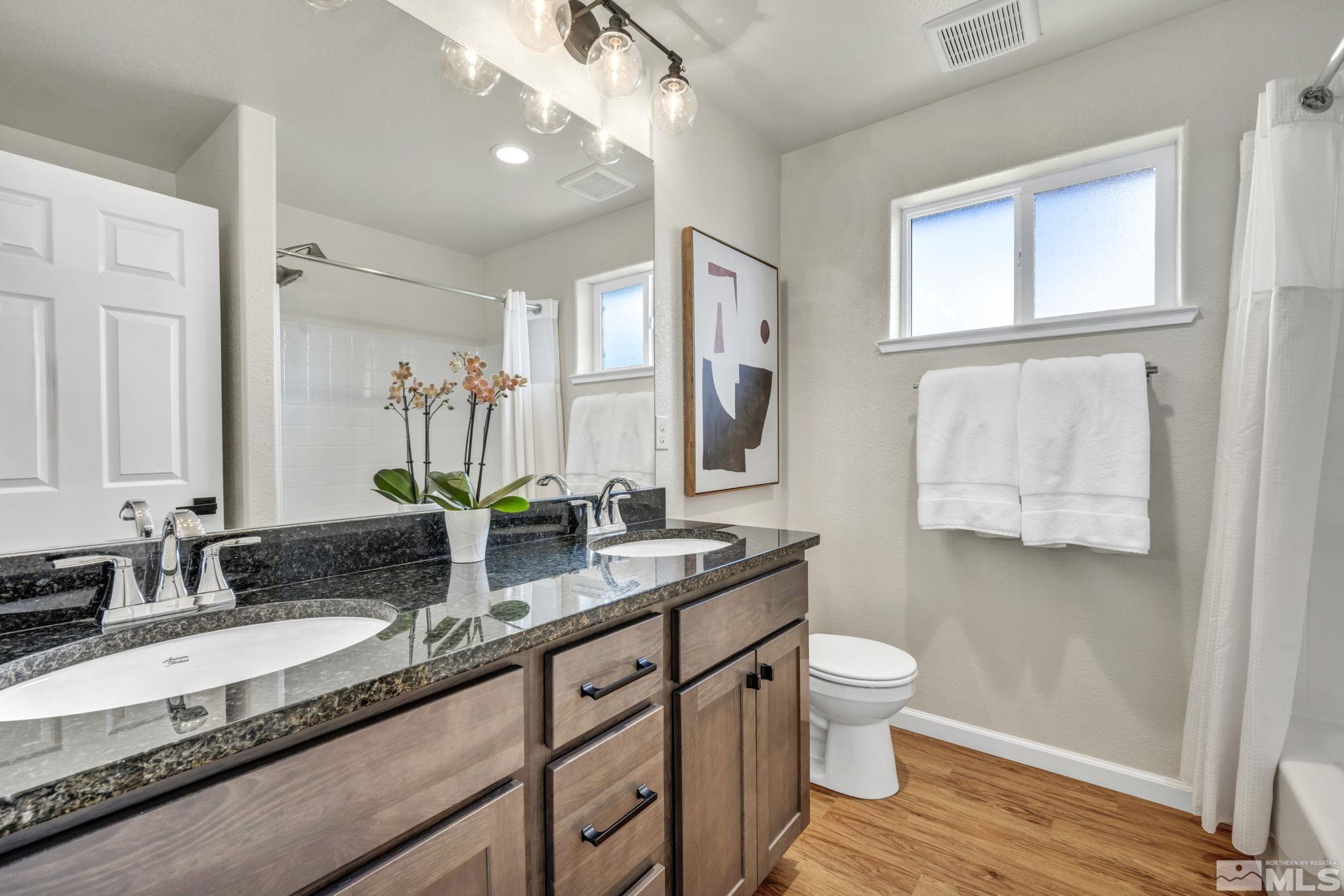 1433 Washington Street Reno, NV 89503 - Photo 29 of 35 a bathroom with a granite countertop sink a toilet a mirror and a window