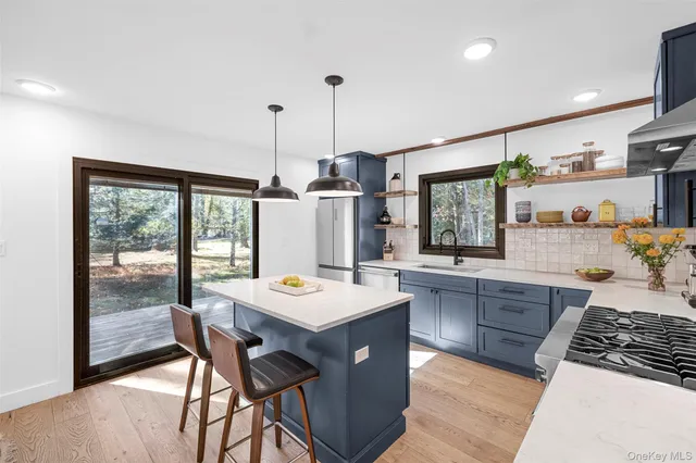 a kitchen with a stove a sink a counter top space and living room view