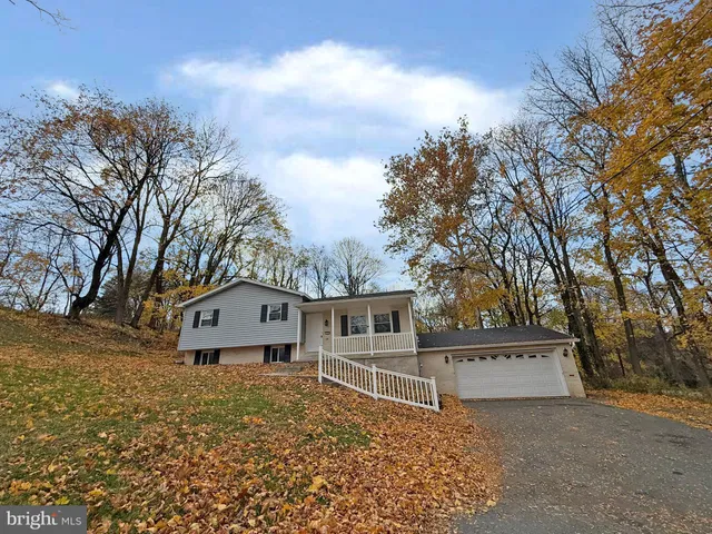 a view of a house with a large tree and wooden fence