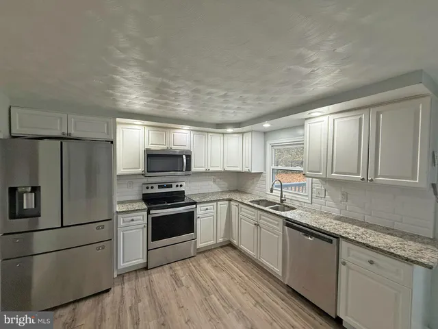 a kitchen with stainless steel appliances granite countertop a stove a sink and a refrigerator