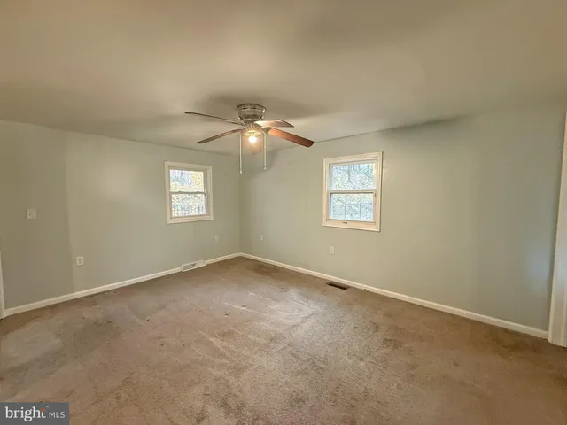 an empty room with windows and fan