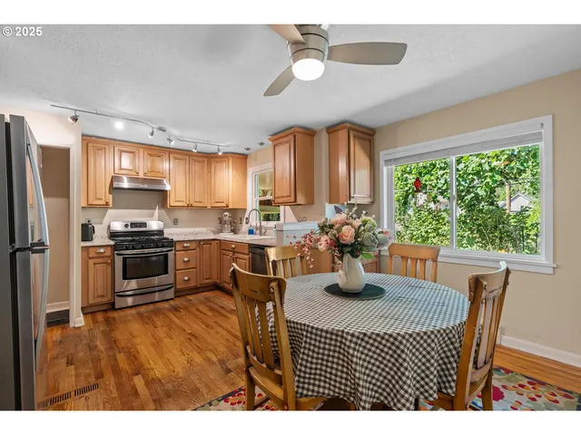 a kitchen with granite countertop a refrigerator a stove a sink dishwasher a dining table and chairs with wooden floor